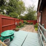 Garden with red fence and patio area.