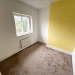 Empty room with yellow accent wall and window.