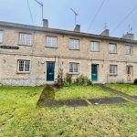 Stone terraced houses with green doors and lawns.