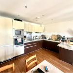 Modern kitchen with appliances and wooden flooring.