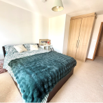 Bright bedroom with double bed and wooden wardrobe.