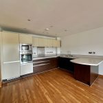 Modern kitchen with wooden flooring and built-in appliances.