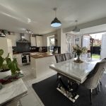 Modern kitchen with dining table and open garden view.