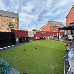 Suburban garden with artificial grass and seating area.