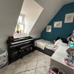 Cosy bedroom with piano and single bed.