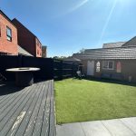 Sunlit backyard with grass and patio table.