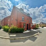 Modern red brick corner house on a sunny street.