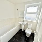 Modern white bathroom with bathtub, sink, and toilet.
