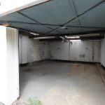 Empty garage with open door and concrete floor.
