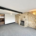 Stone-walled living room with fireplace and carpet floor.