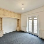 Empty room with carpet, built-in shelves, and French doors.