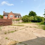 Vacant backyard with concrete and overgrown grass.