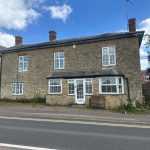 Stone house with white-framed windows, bench outside.