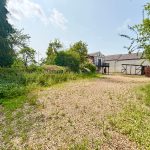 Gravel driveway leading to traditional countryside house.