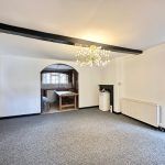 Spacious room with chandelier and archway to kitchen.