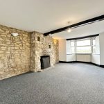 Spacious room with stone fireplace and bay window.
