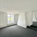Bright, carpeted room with window and steps.