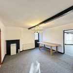 Spacious room with table, chandelier, and wooden bookshelf.