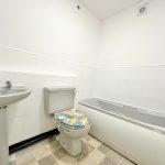 White bathroom with bath, sink, and toilet.