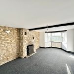 Spacious room with stone fireplace and large window.