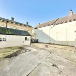 Sunny courtyard between old stone buildings.