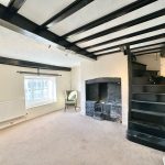 Traditional room with fireplace and wooden staircase.