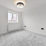 Empty white room with grey carpet and window.