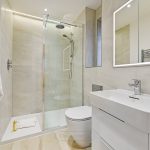 Modern bathroom with shower, sink, and robe.