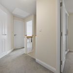 Carpeted hallway with white doors and bannister