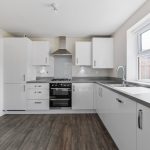 Modern kitchen with white cabinets and wooden floor.