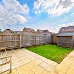 Backyard with patio, shed, and grass.