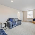 Spacious living room with sofas and carpeted floor.