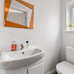 Modern bathroom with orange mirror and window.