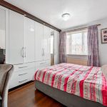 Modern bedroom with white wardrobe and colourful bedding.