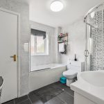 Modern bathroom with shower, bath, and tiled walls.
