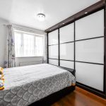 Modern bedroom with sliding wardrobe and window light.