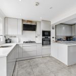 Modern white kitchen with island and appliances.