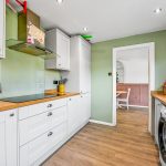 Modern kitchen with green walls and wooden countertops.