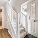 Modern hallway with staircase and bathroom entrance.
