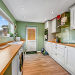 Modern kitchen with wooden countertops and green walls.