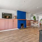 Modern living room with blue fireplace and dining area.