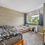 Cosy children's bedroom with twin beds and window view.