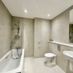 Modern bathroom with bathtub, toilet, sink, and mirror