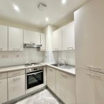 Modern white kitchen with stainless steel appliances.