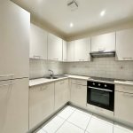 Modern kitchen with white cabinets and tiled backsplash.