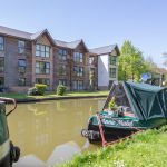 Canal boat moored by modern riverside flats.