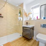 Modern bathroom with walk-in shower and wooden floor.