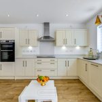 Modern kitchen with white cabinets and wooden floor.