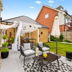 Modern patio with garden furniture and green lawn.