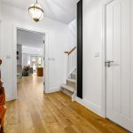 Modern hallway with wooden flooring and sculpture.